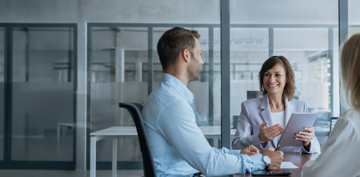 Senior business mentor discussing a project with colleagues on a tablet in an office