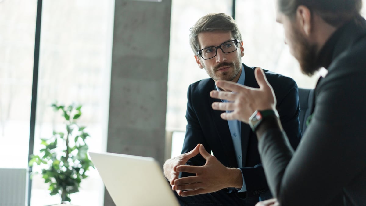 Two business partners discussing strategy across a table in a modern office